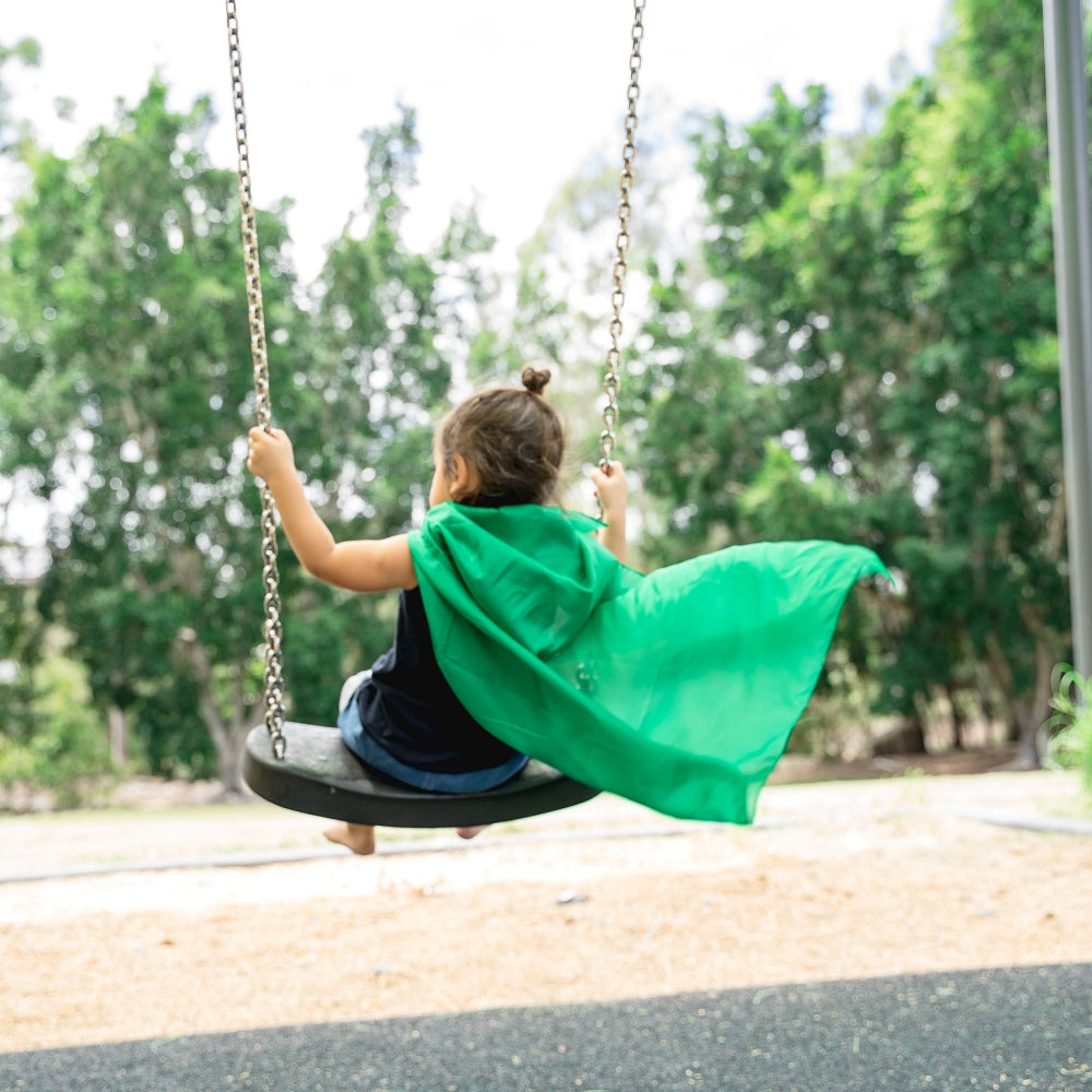 Girl using Green Sarah's play silk as cape sitting on swing