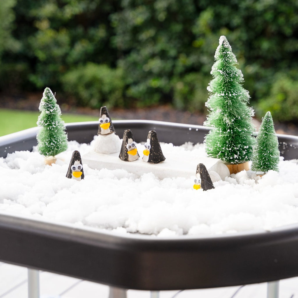 Sensory snow on mini tuff tray with penguins and fir trees
