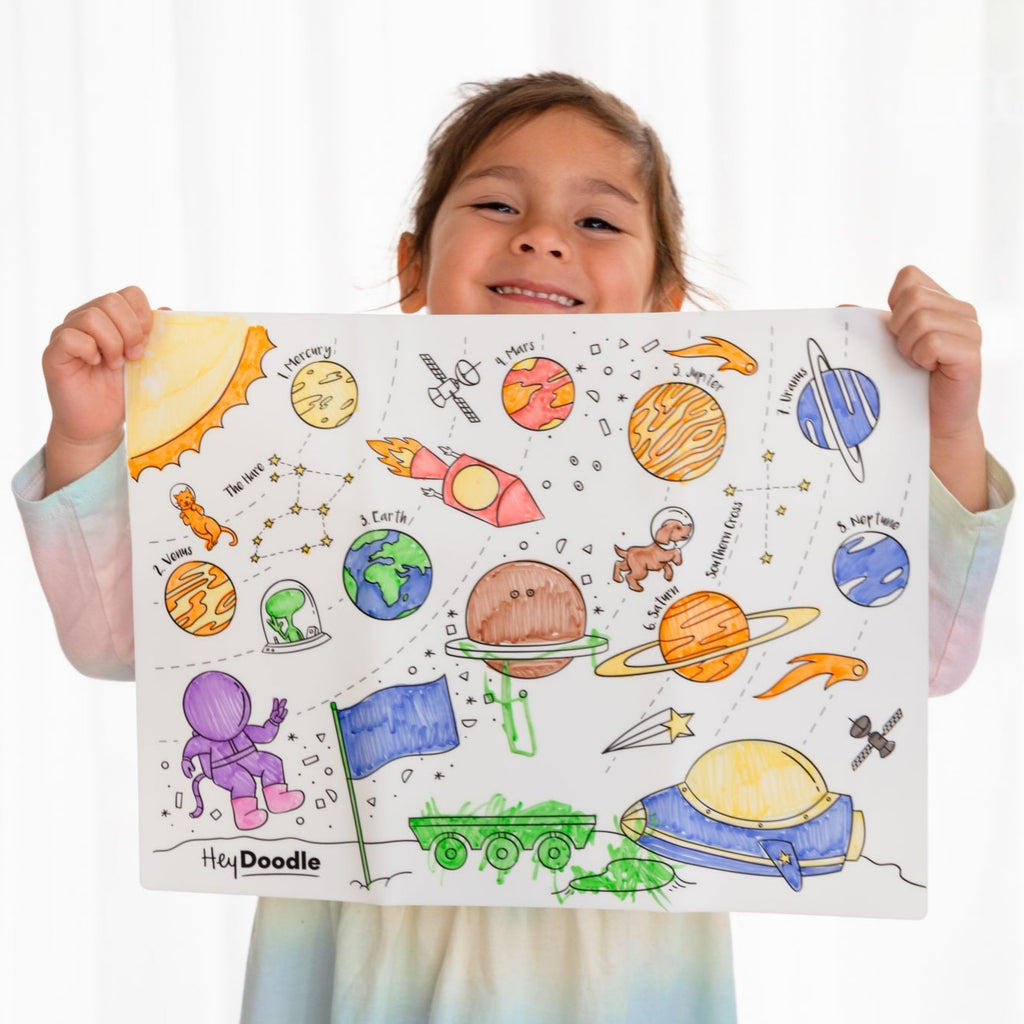 Child holding up outer space mat coloured in 