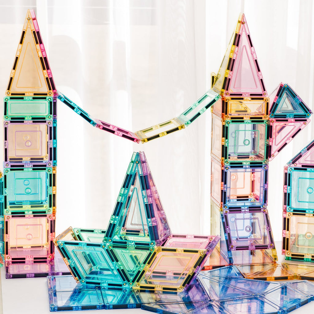 Pastel magnetic building blocks on a white surface with a light curtain background
