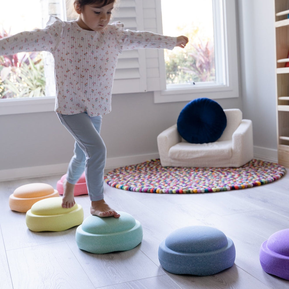 Child stepping on pastel stapelstein in playroom