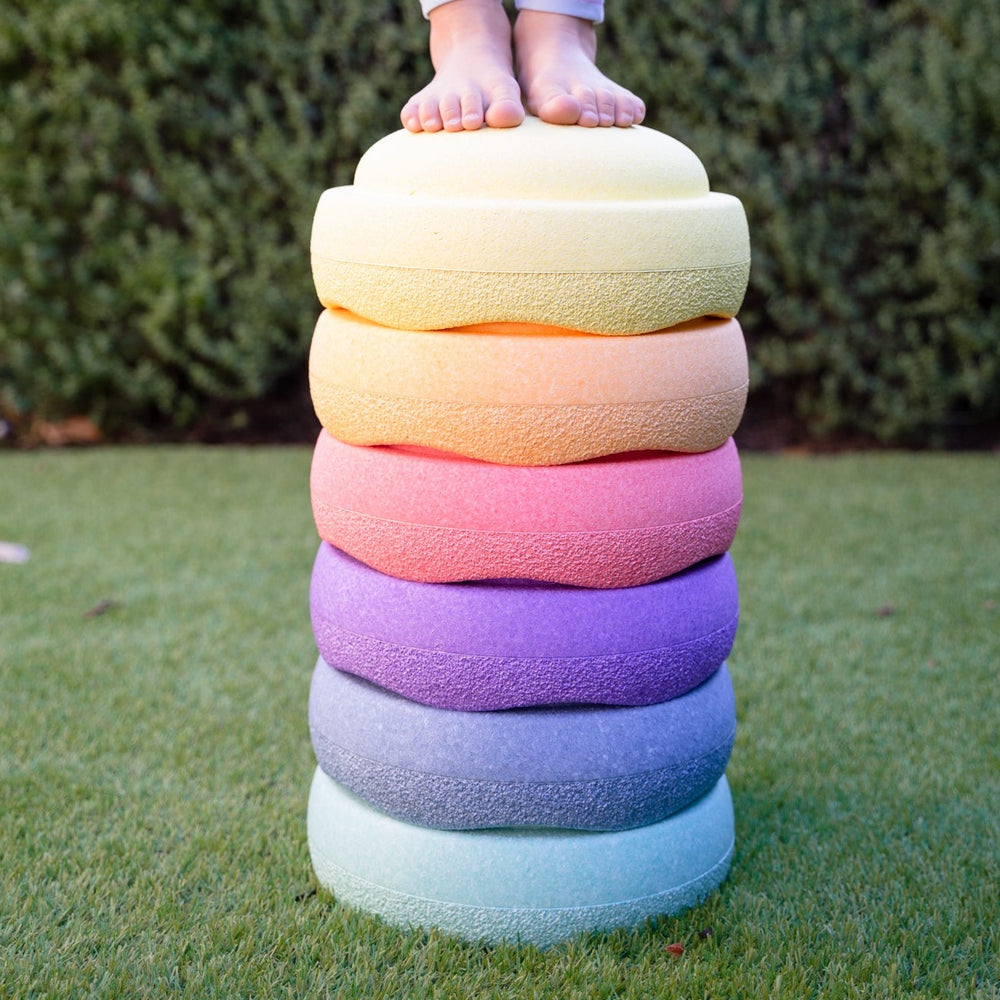 Child standing on pastel stapelstein stacked outside on grass