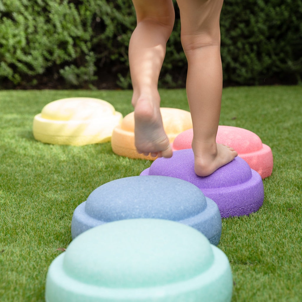Child stepping on pastel stapelstein outside