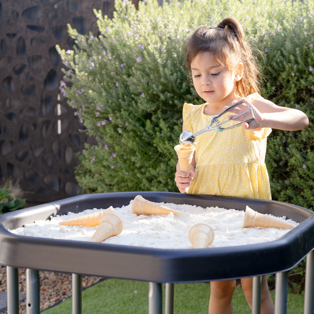 Child playing with sensory sand and ice cream cones on a mini tuff tray outside