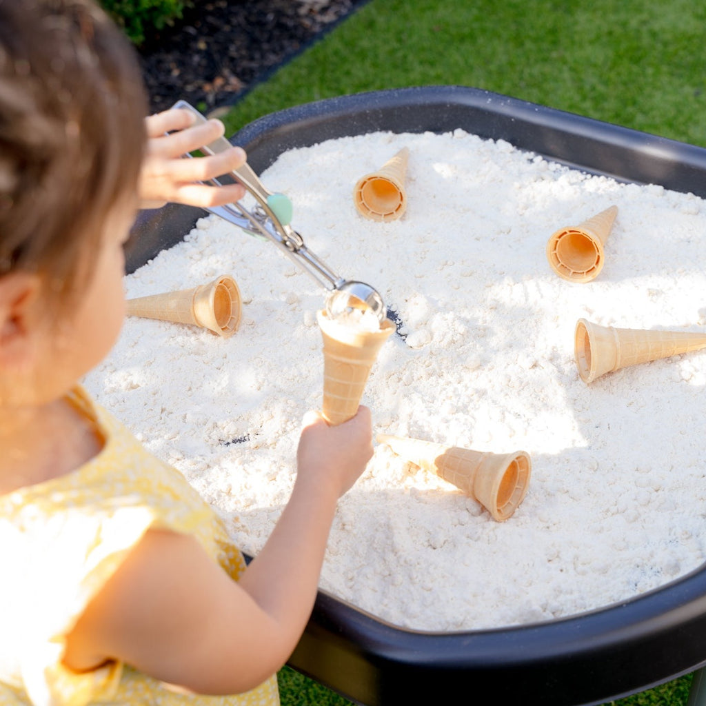 Child playing with sensory sand and ice cones on a mini tuff tray outside
