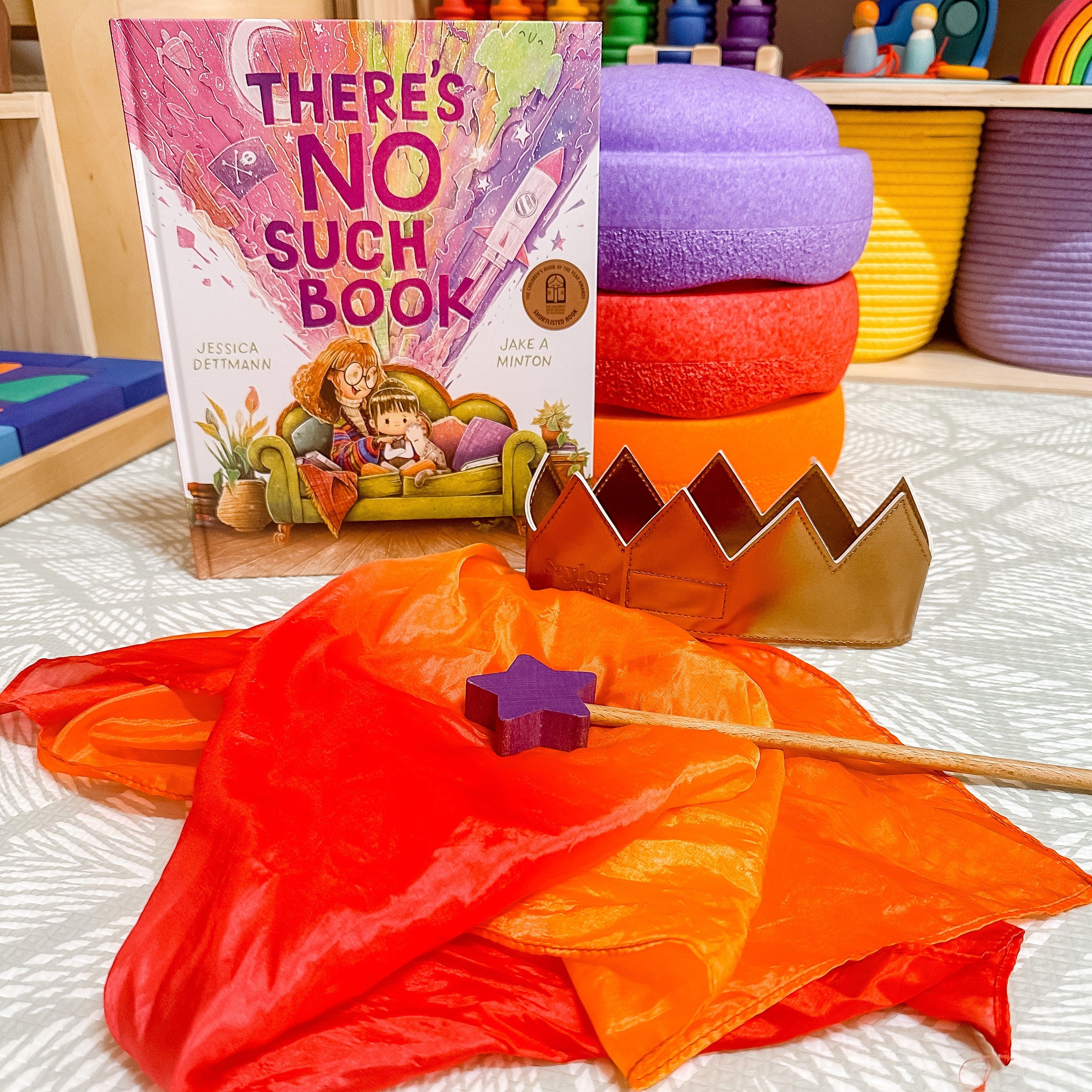 Books from a monthly book subscription displayed with wand, cape and crown for dress up play