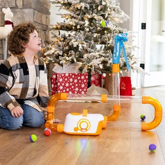 Child playing with a air toobz toy on the floor in a room decorated for Christmas.