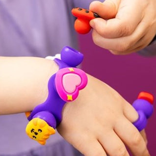 Child wearing a colourful bracelet with charm characters on a purple background