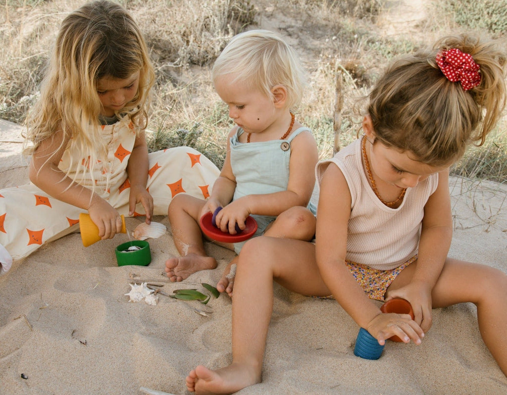 Children playing with rainbow wooden pots from Grapat 2024 release at the beach 