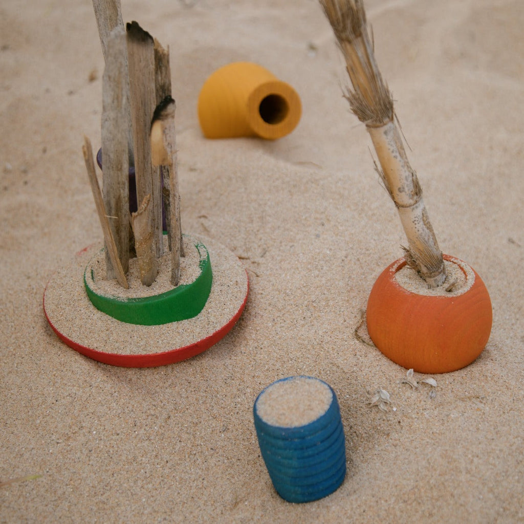 Grapat wooden rainbow pots at the beach filled with sand and sticks