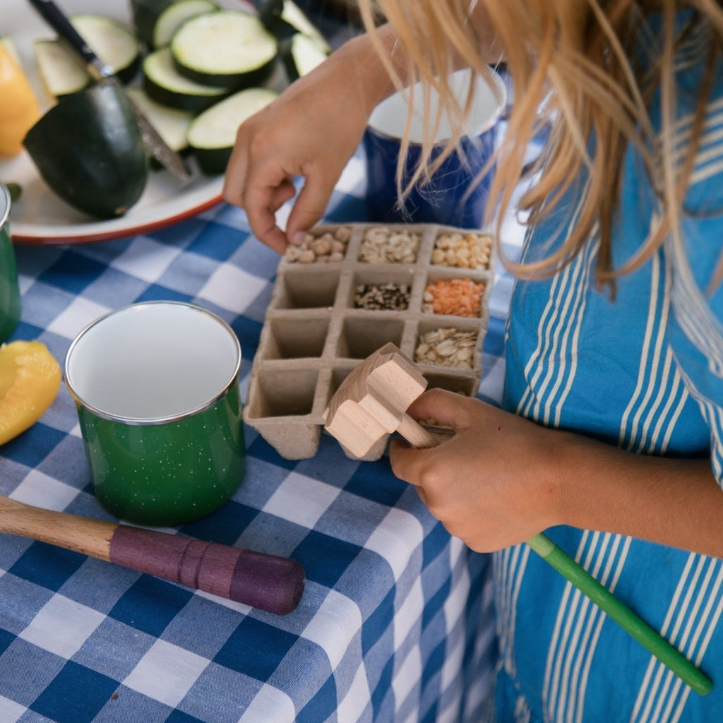 New Grapat fine motor tools being held by a girl going through sensory food items in a cardboard carton on a table with vegetables