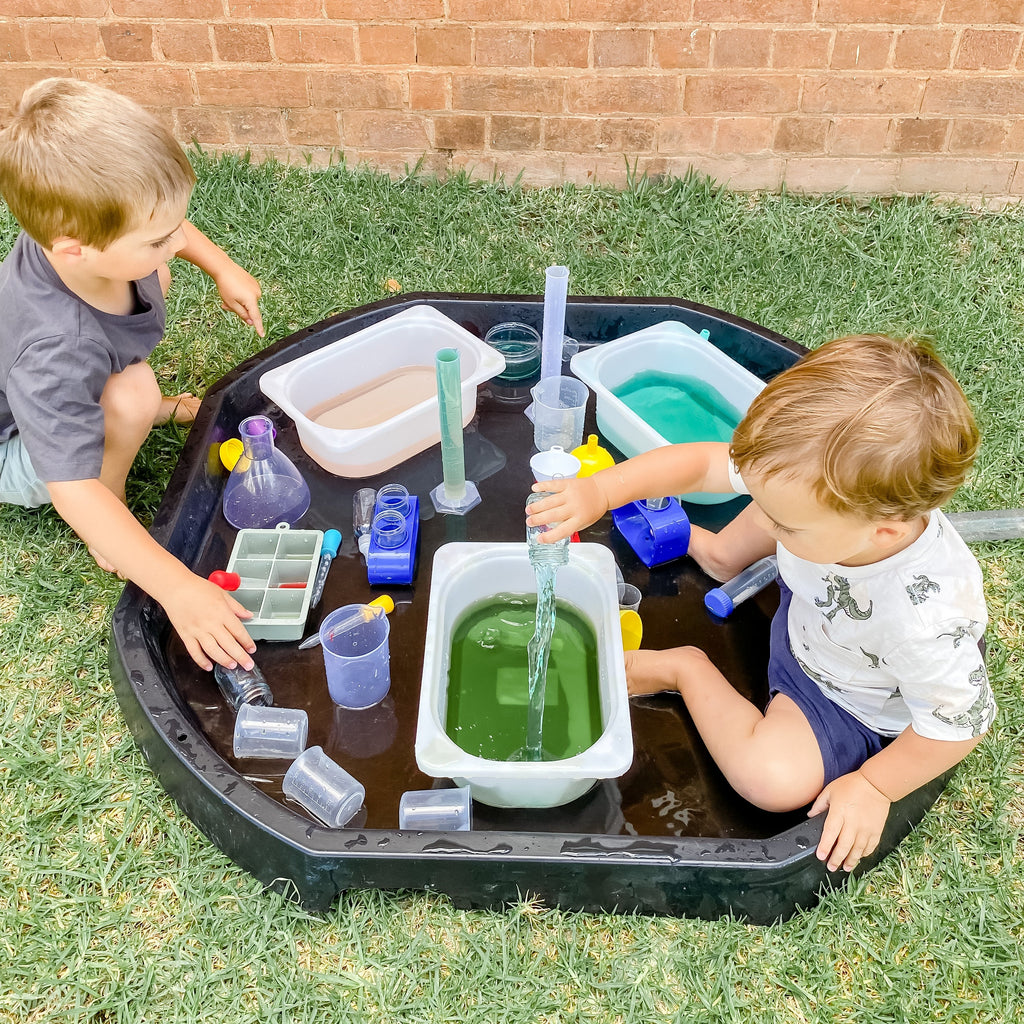 Boys sitting in tuff tray doing water play and experiements