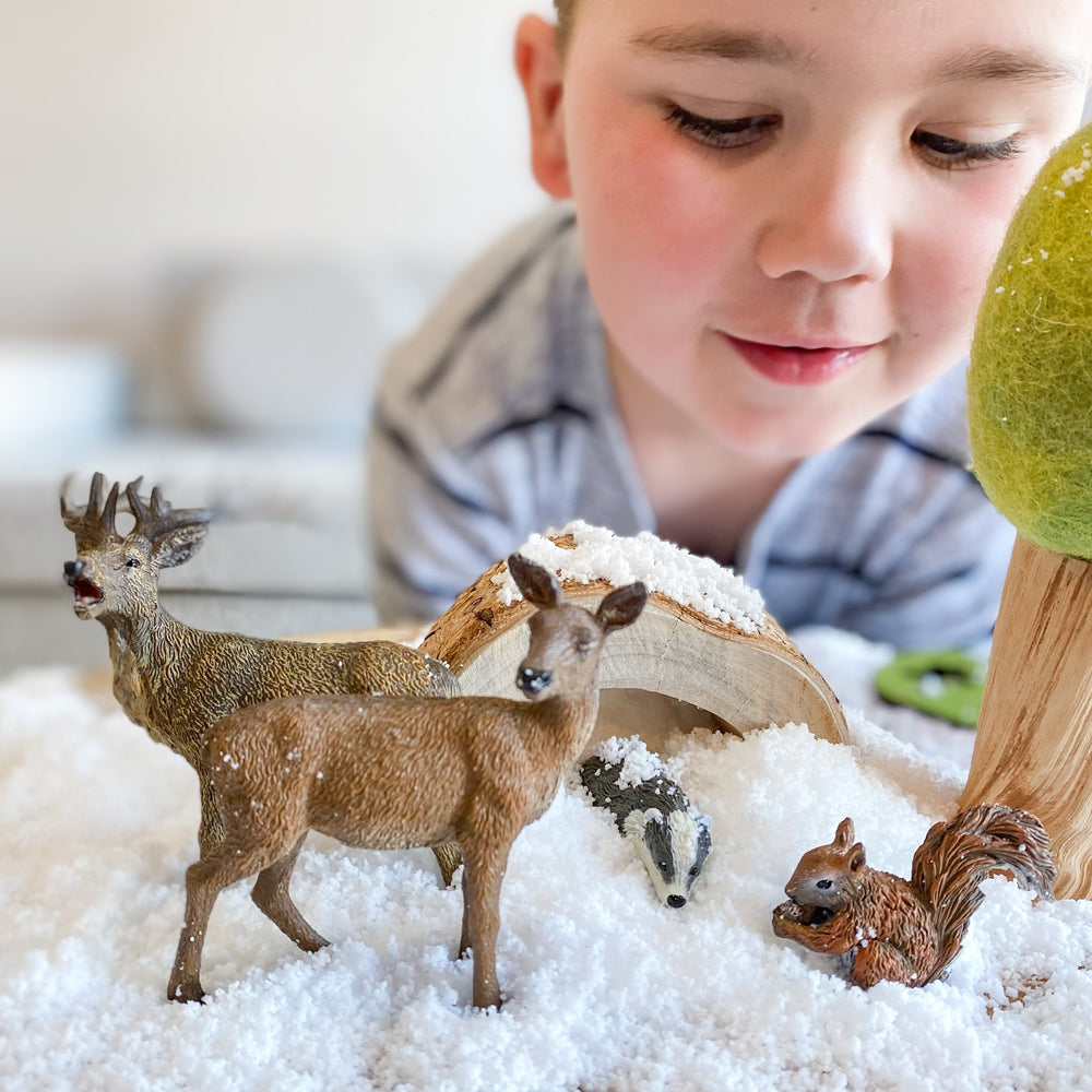 Child playing with sensory snow and woodland themed CollectA animals