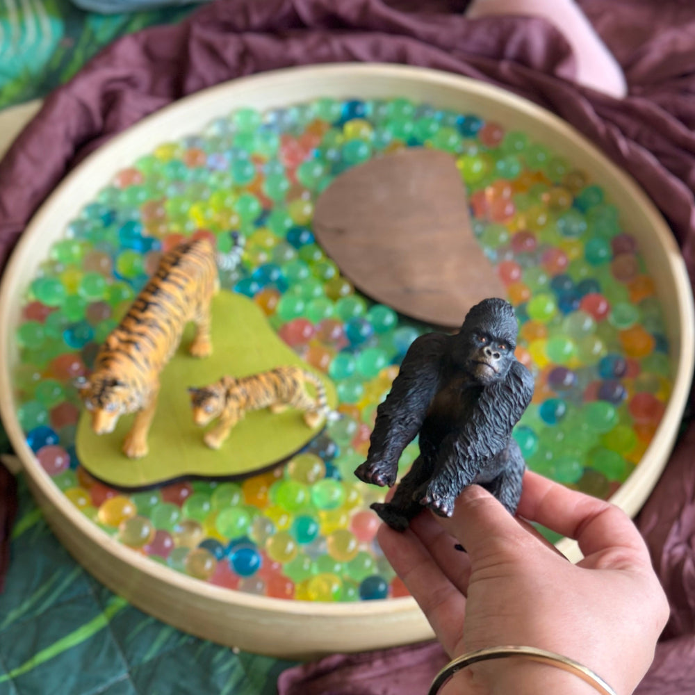 Person  holding collecta gorilla with sensory tray and wild animals in background