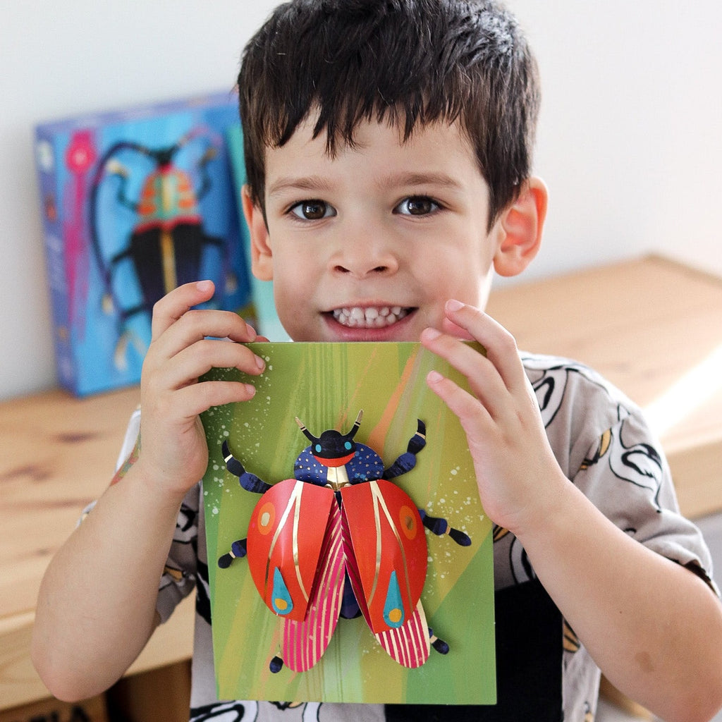 Child holding 3d bug art from Djeco