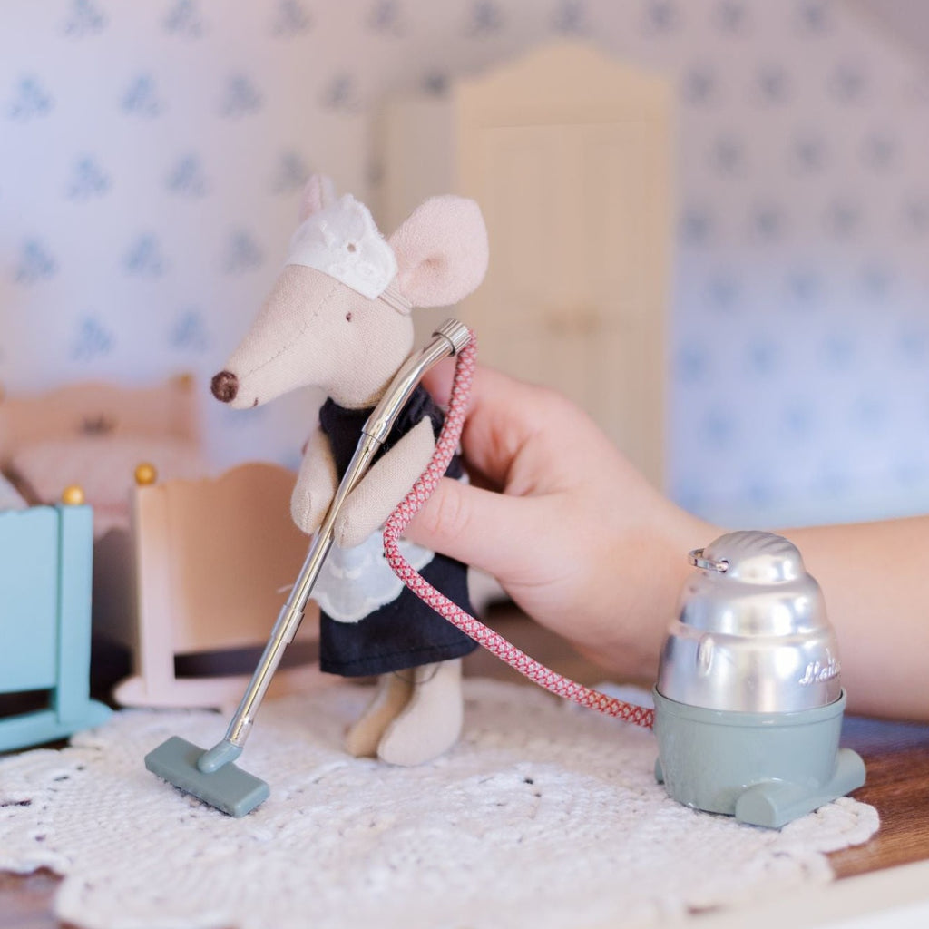 Mouse maid cleaning room with Maileg Vacuum Cleaner sitting in dollhouse with blue and pink cradle in background