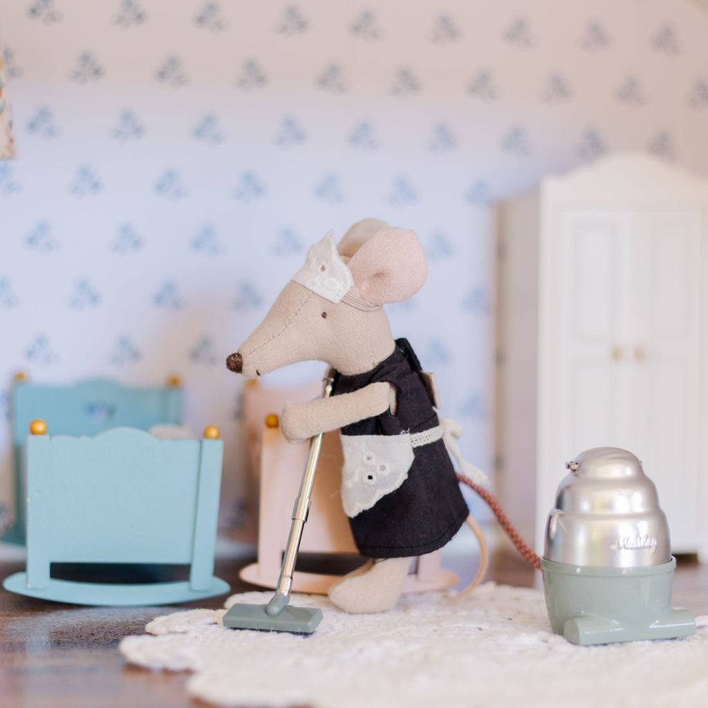 Mouse maid using Maileg Vacuum Cleaner sitting in dollhouse with blue and pink cradle in background