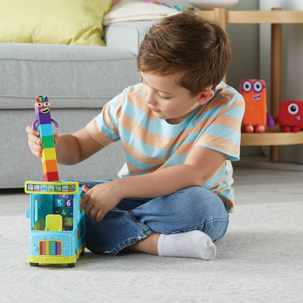 Child playing with Numberblocks Rainbow Counting Bus on the floor with couch behind