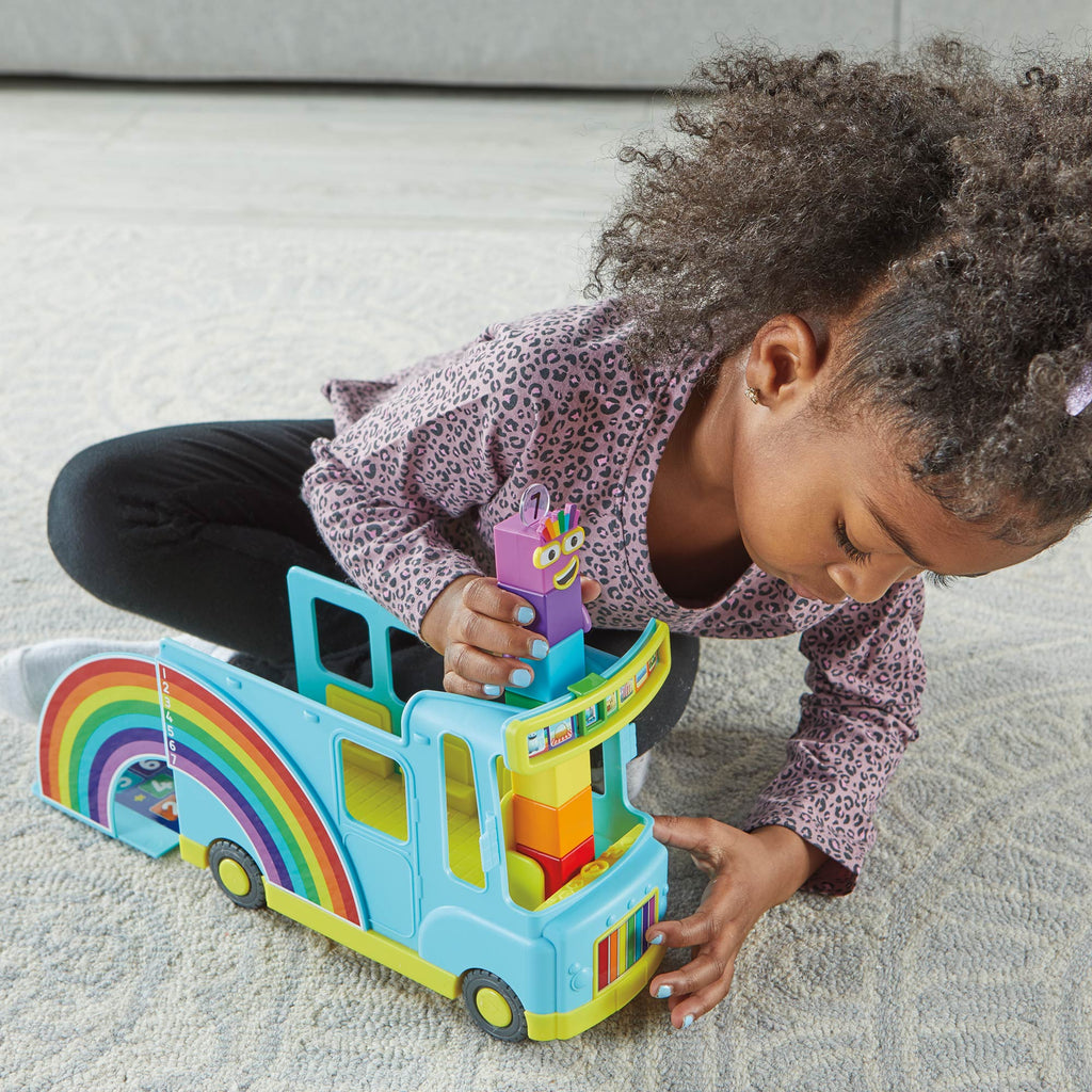 Child playing with Numberblocks Rainbow Counting Bus on the floor with couch behind 