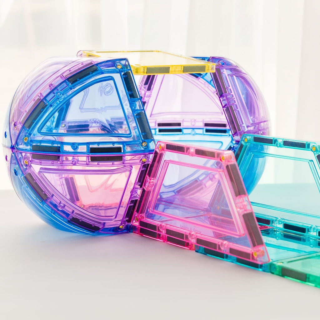 Pastel transparent geometric magnetic tiles on a white surface with a light background