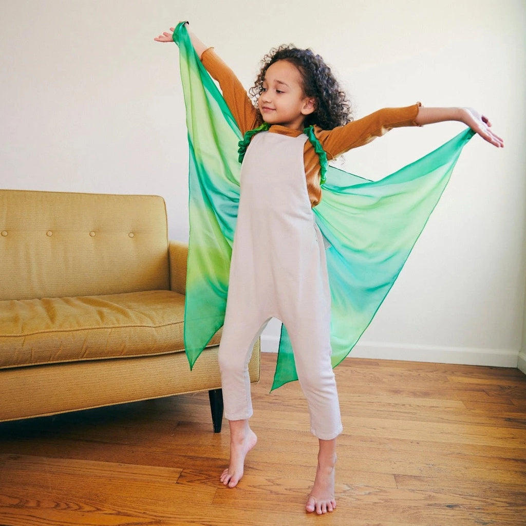 Child wearing forest fairy wings with arms outstretched