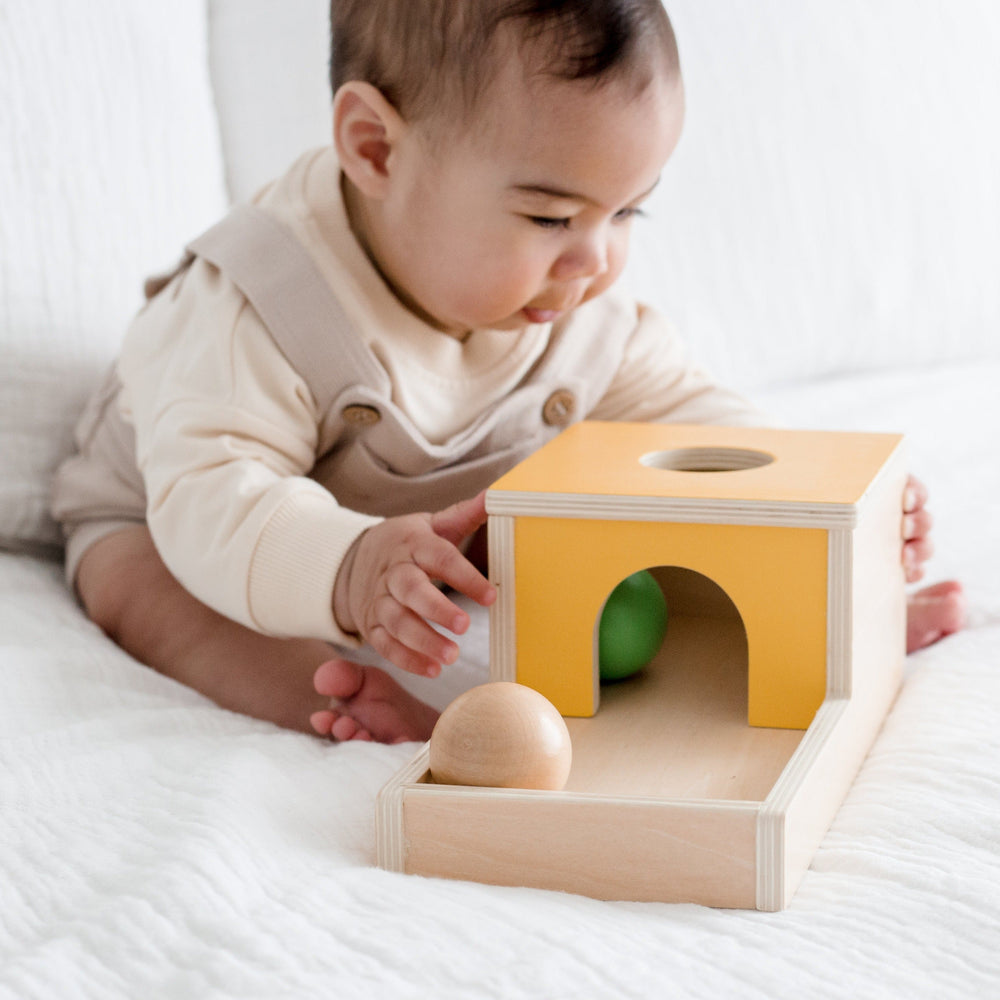 Toddler on bed playing with The Totli Ball Drop a montessori inspired baby toy