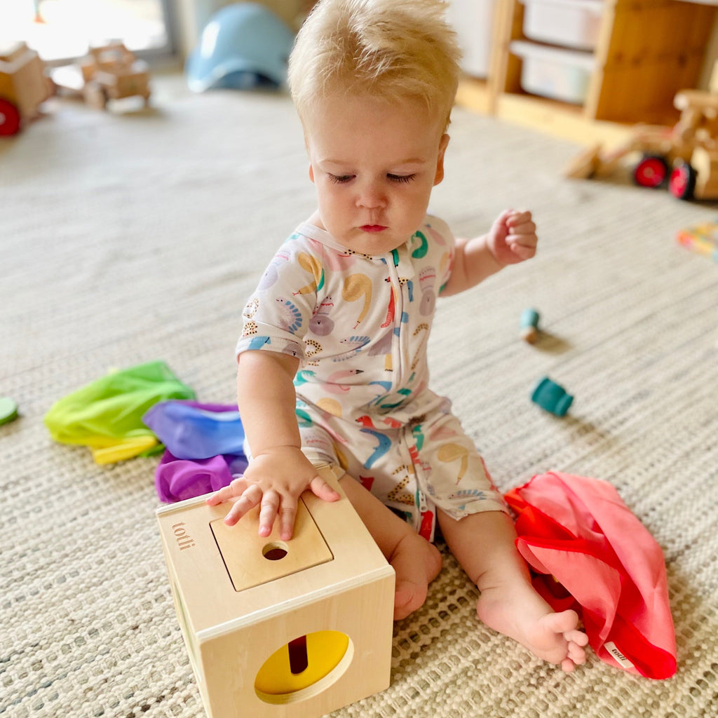 Baby playing with montessori Totli Box with scarves on floor