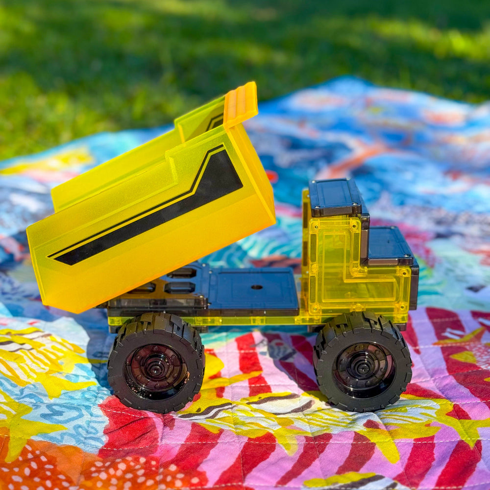 Toy dump truck on a colourful  play mat with grass in the background