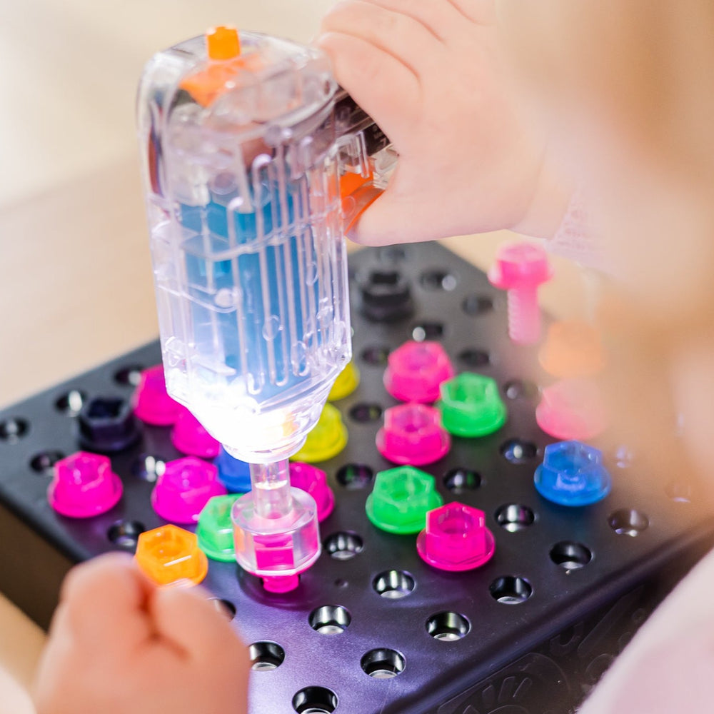 Child using light up drill and the drill is shown lit up with board of nuts and bolts