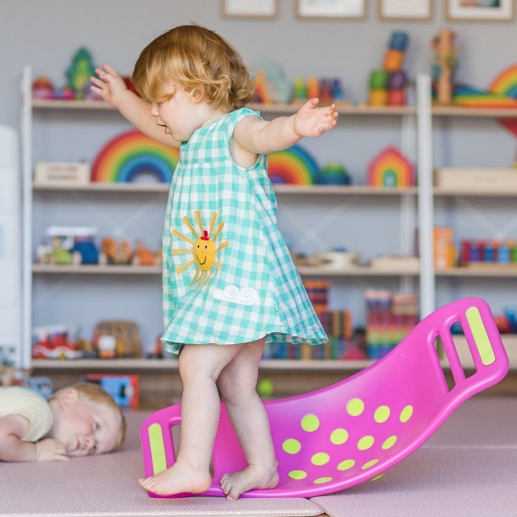 Fat Brain Toys - Teeter Popper being played with by a child in a playroom with rainbow wooden toys