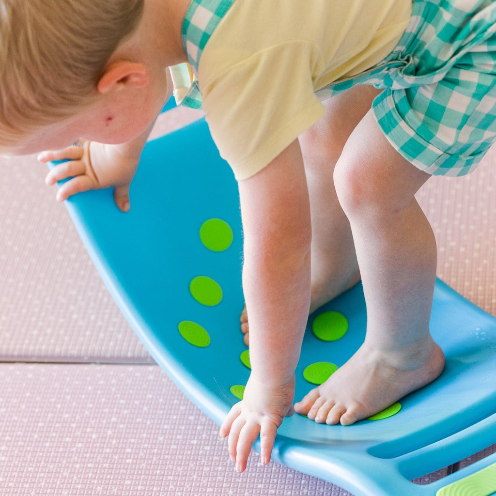 Fat Brain Toys - Teeter Popper being stood on by on a boy balancing it on a play mat