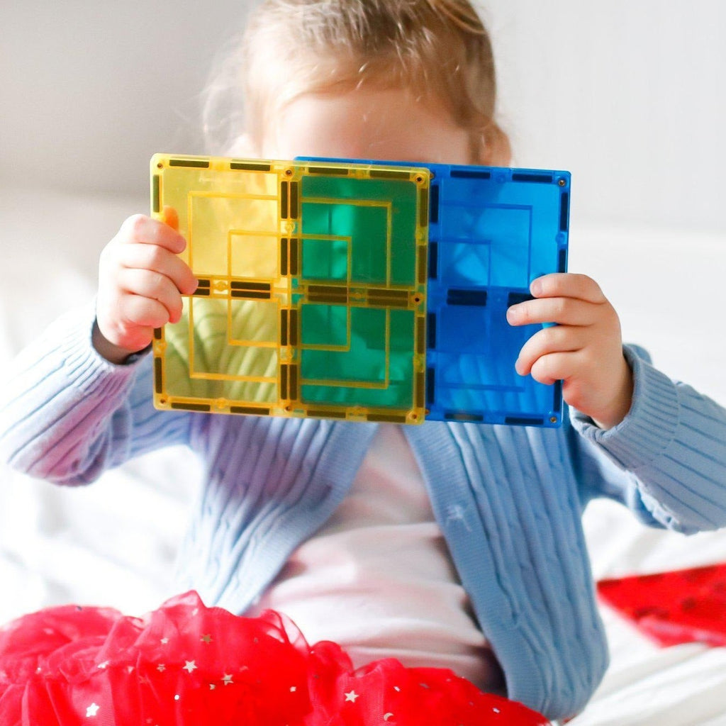 Little girl in a red tutu playing with yellow and blue large square tiles from Learn and Grow toys 