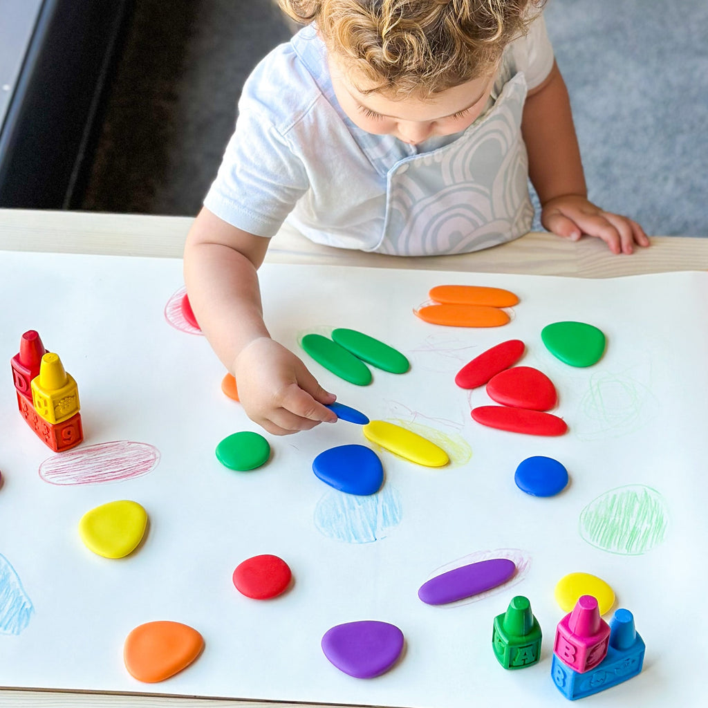 Child using crayons around rainbow junior pebbles