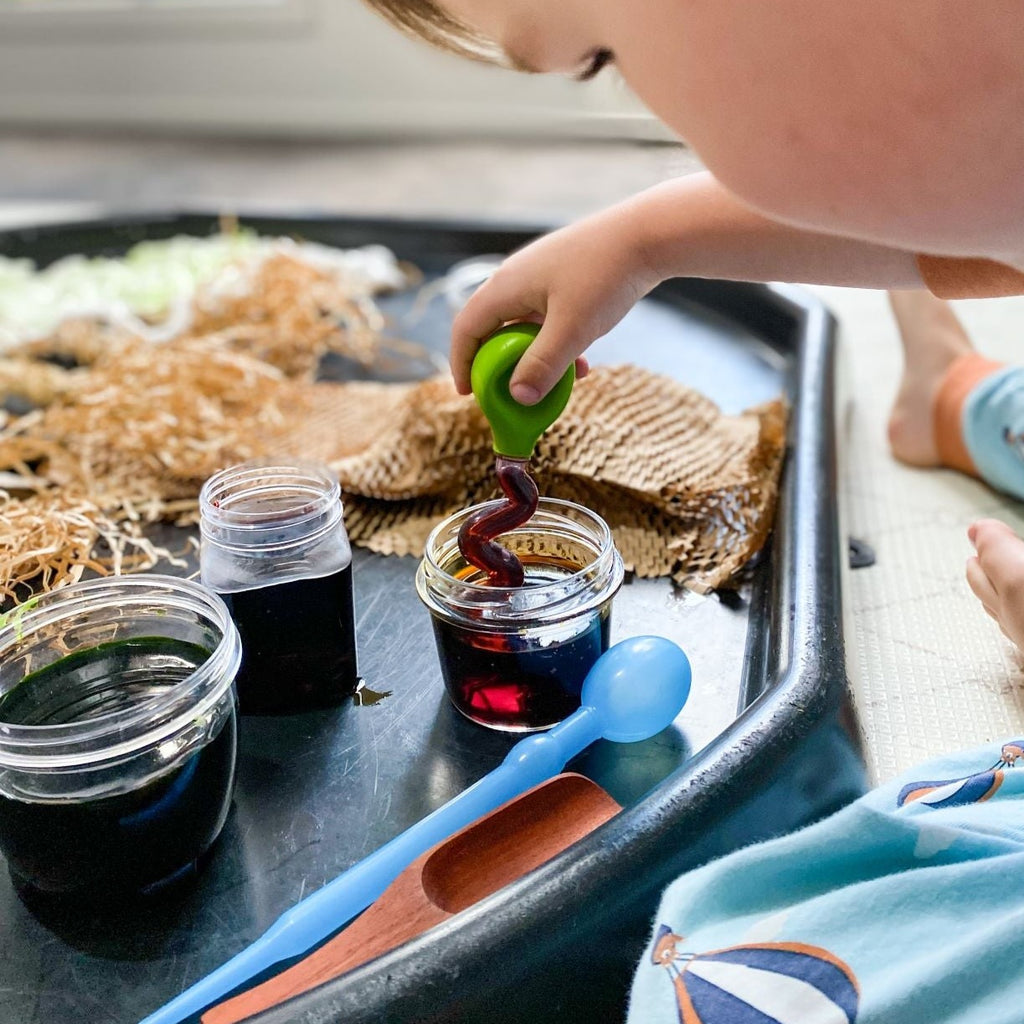 Child playing with sensory materials on a black tuff tray
