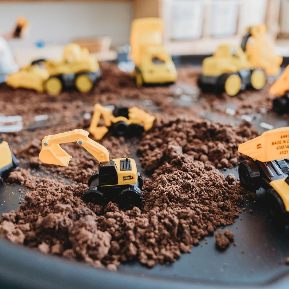 Construction play with kinetic sand and diggers on a tuff tray