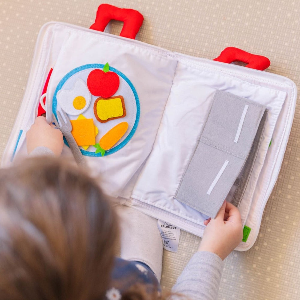 Girl playing with book moving fabric items from fridge to fry pan