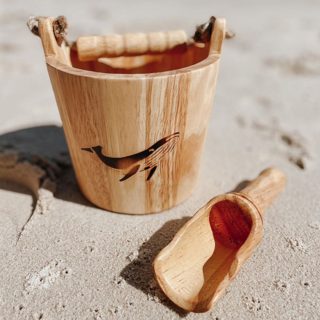 Wooden bucket and scoop with whale burn on front on sandy beach