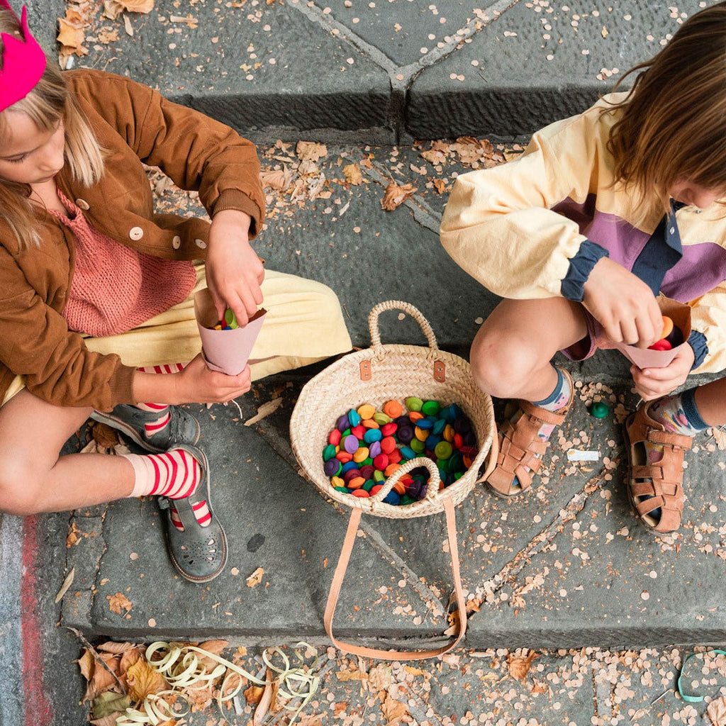 Children playing with wooden rainbow flower mandalas sitting on steps