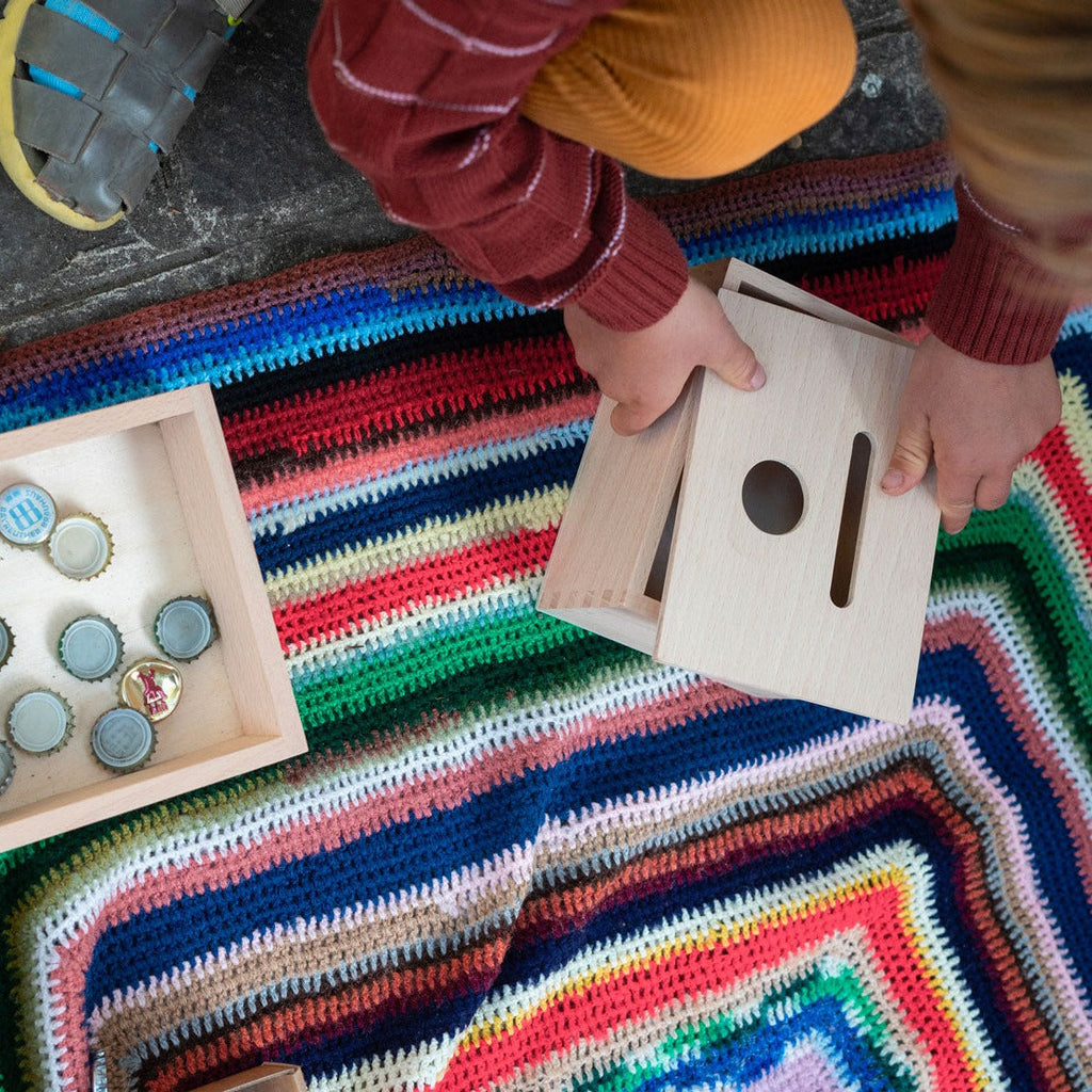 Child playing with Grapat Permanence Box sitting on a colourful rug