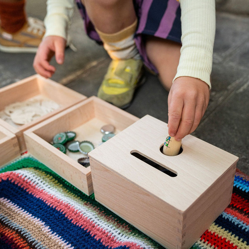Child playing with Grapat Permanence Box sitting on a colourful rug