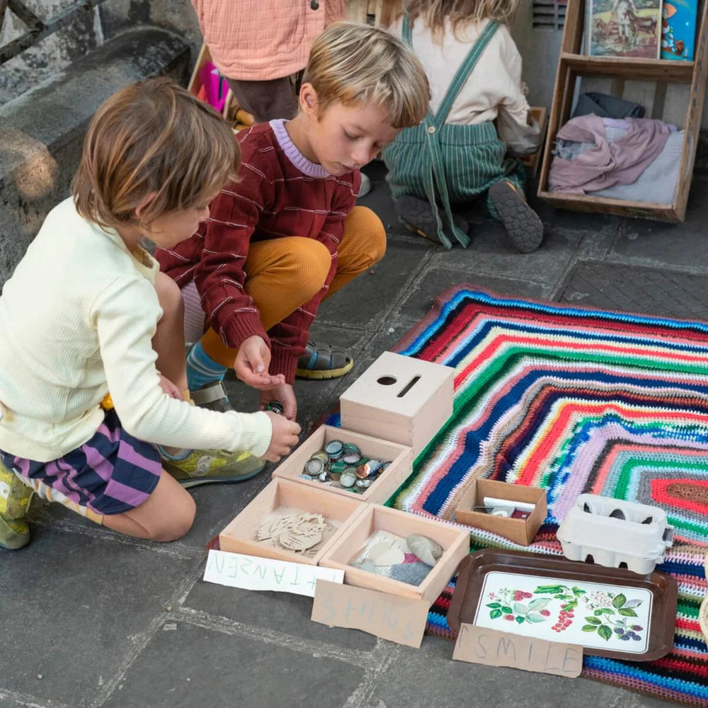 Children playing with Grapat Permanence Box sitting on a colourful rug in a city street
