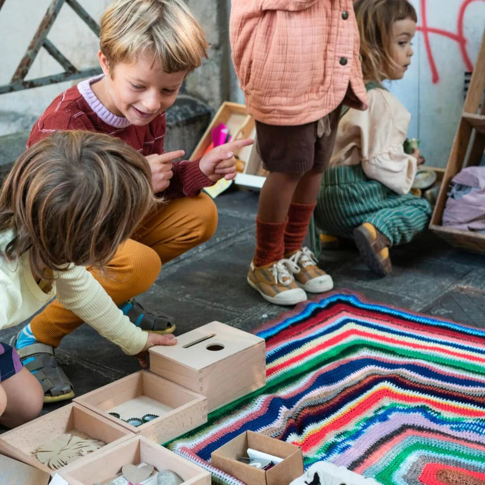 Children playing with Grapat Permanence Box sitting on a colourful rug in a city street