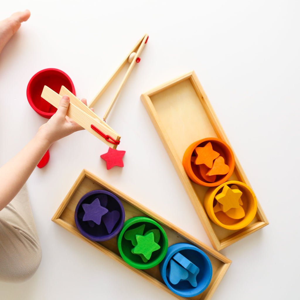 Rainbow sorting game with child holding tongs 