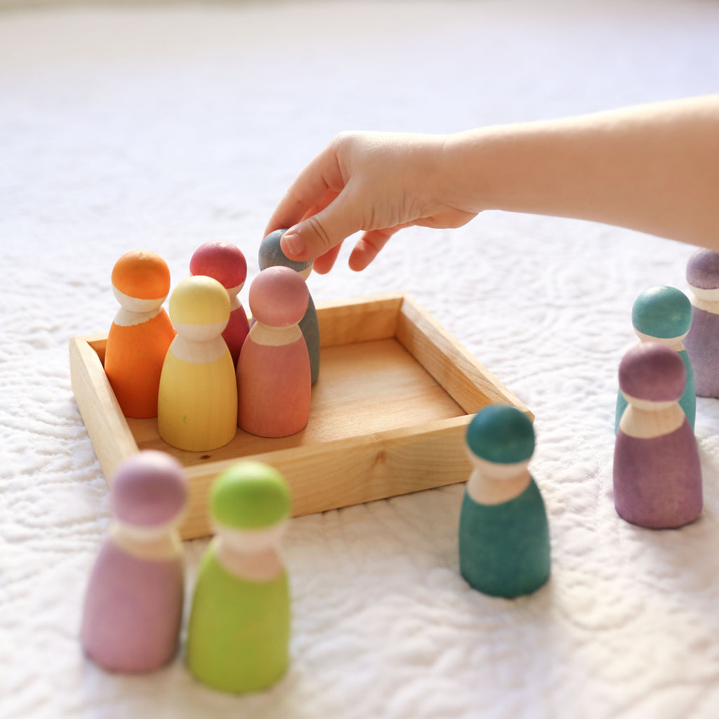 Grimm's 12 rainbow friends in pastel being played with by a child