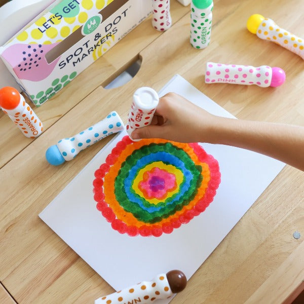 Spot and Dot markers being used to create a rainbow dot picture by a child