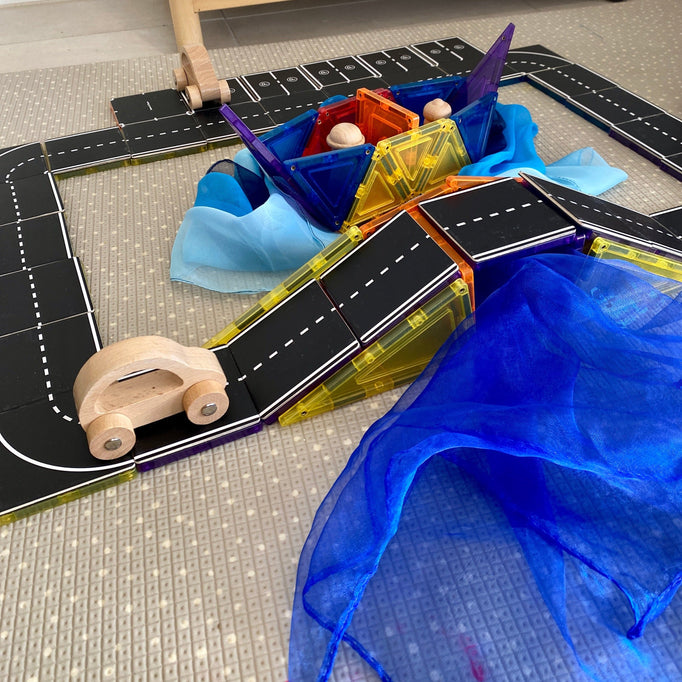 Magnetic tile road toppers added to tiles to create a road set up wooden car driving up hill
