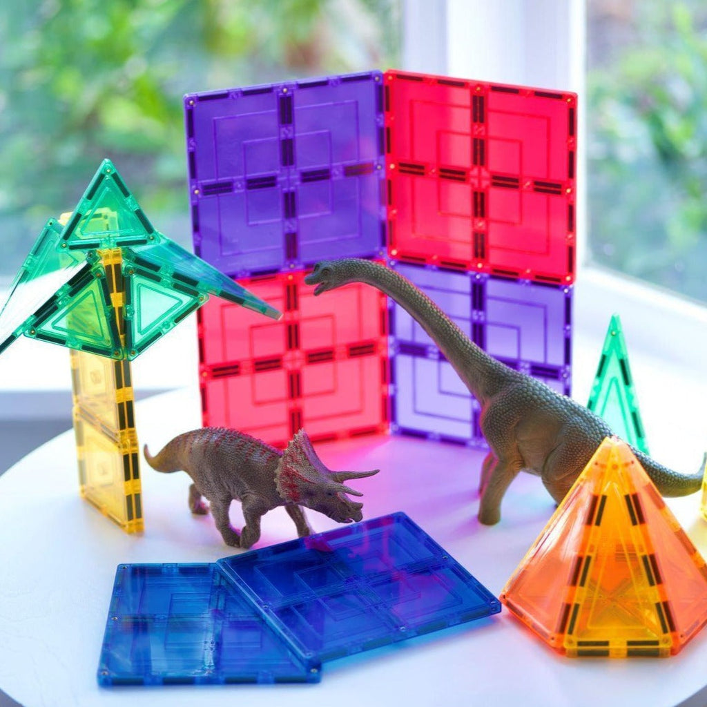 Purple and red large square tiles , plastic dinosaur toys and magnetic tiles set up on a table 