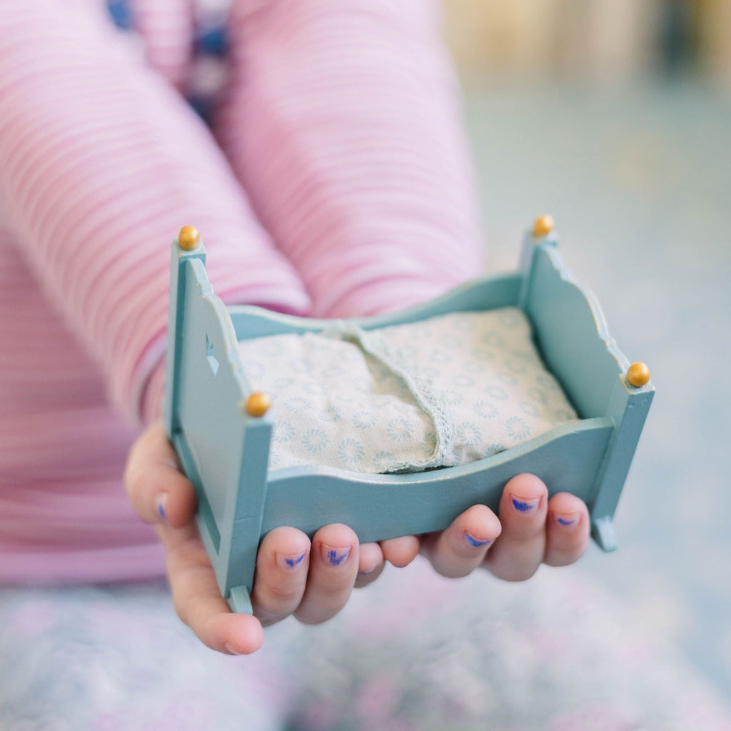 Child holding baby mouse blue cradle